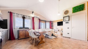 Une cuisine avec une table à manger, des chaises, un téléviseur et une vue sur la mer.