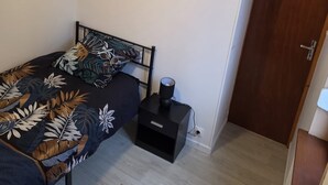 Ett sovrum med en säng, ett nattduksbord, en lampa och en dörr.
