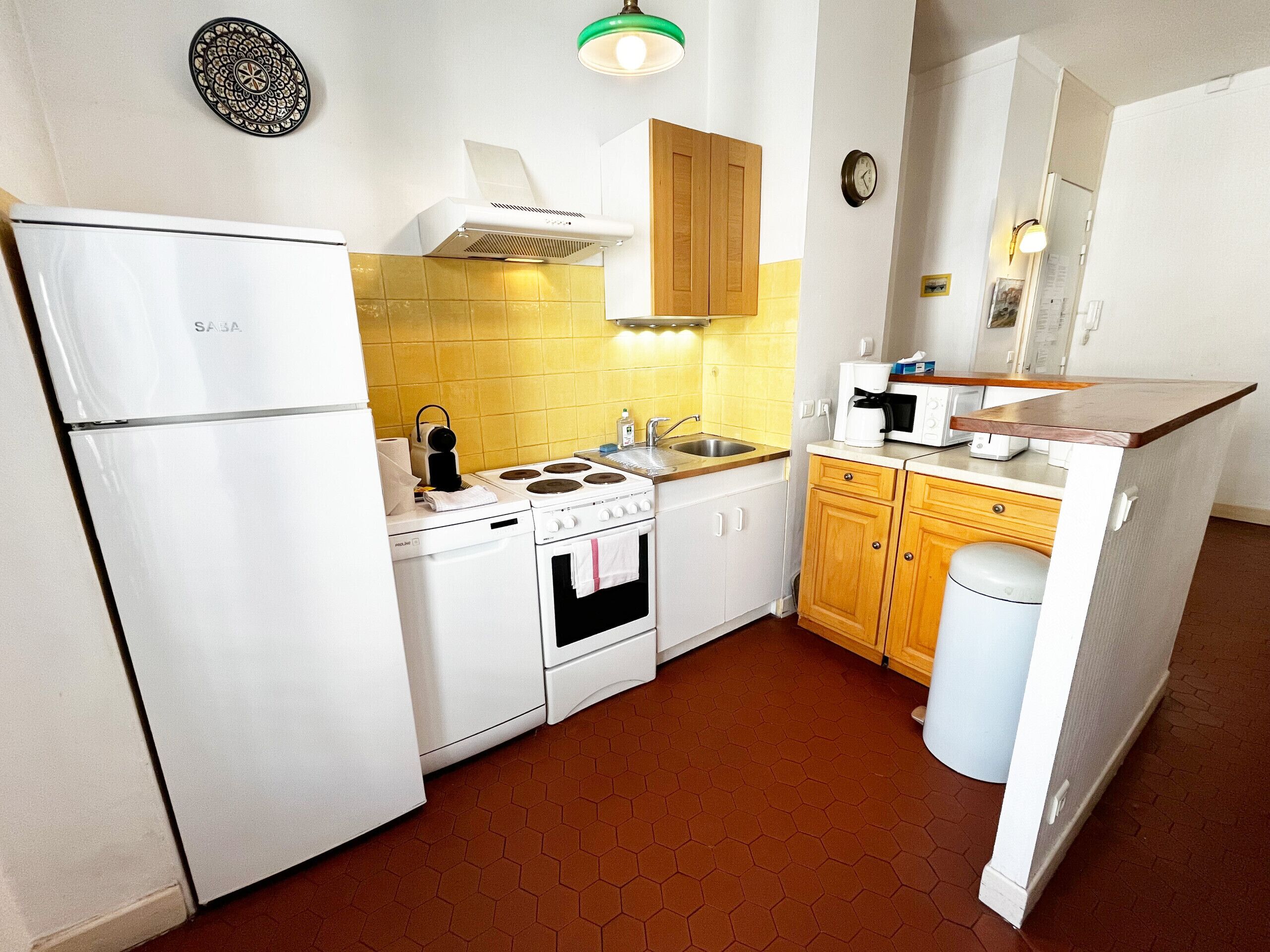 A compact kitchen with a refrigerator, stove, sink, and wooden cabinets.