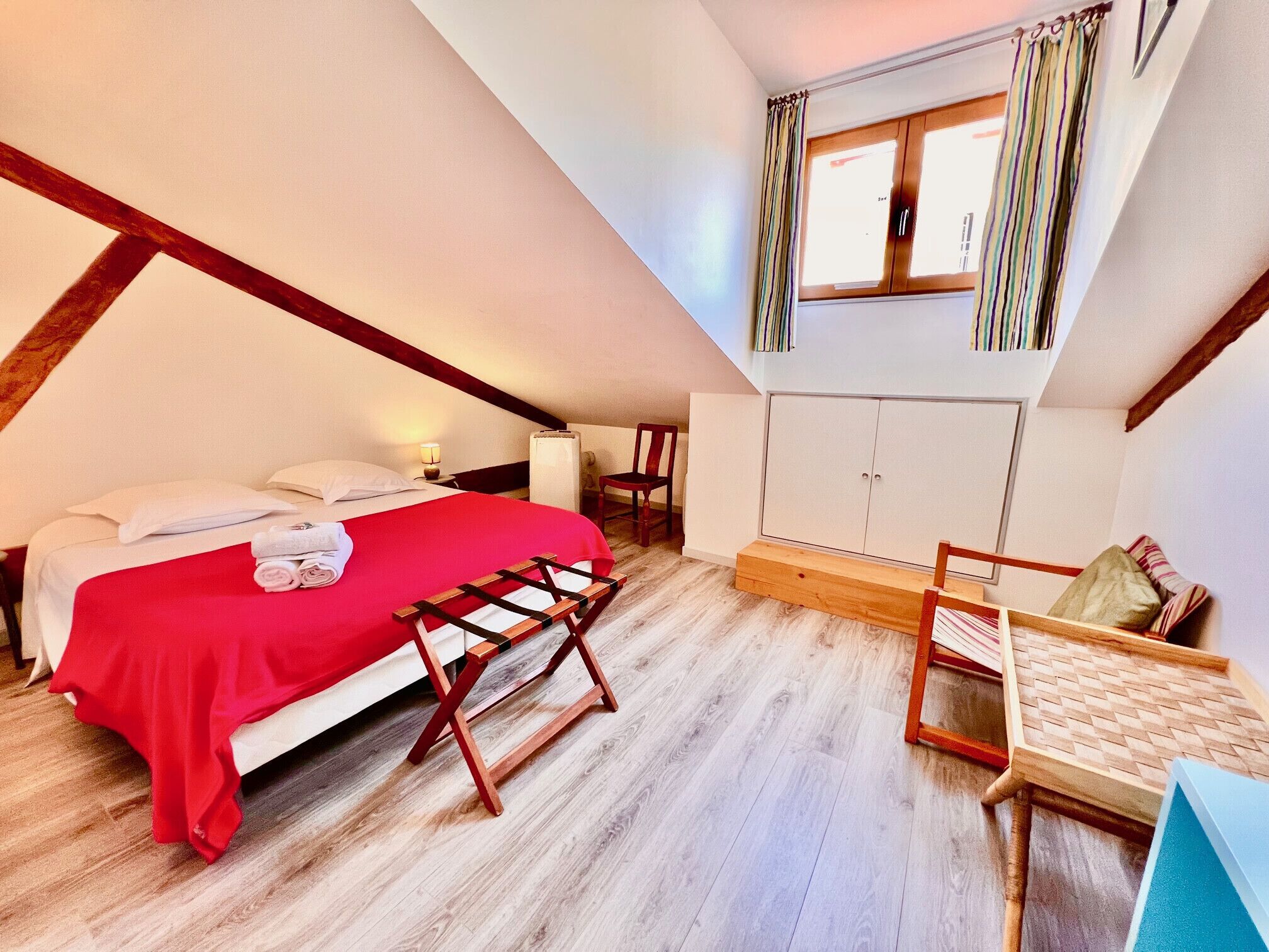 Quarto com cama, escrivaninha, cadeira, guarda-roupa e janela com cortinas.