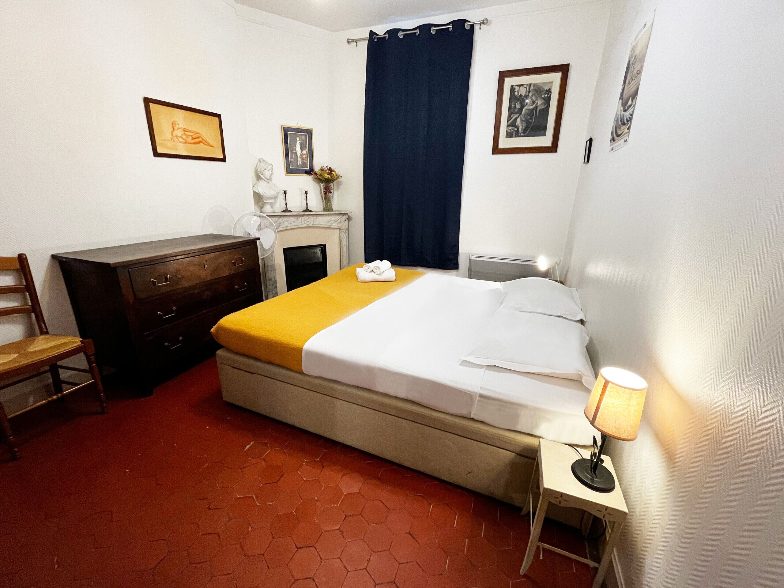 Ein Hotelzimmer mit einem Bett, einem Schminktisch, einem Sessel, einem Schreibtisch mit Lampe und einem Kamin.