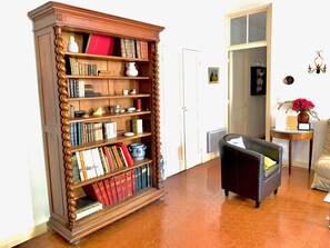 Ein Zimmer mit einem großen Bücherregal, einem kleinen Tisch mit einer Vase und einem Stuhl.