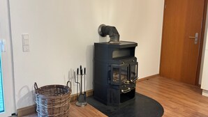 A room with a black wood-burning stove, a wicker basket, and a door.