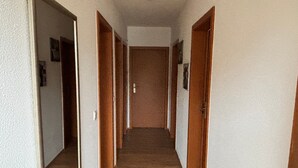 A hallway with wooden flooring, white walls, and wooden doors.