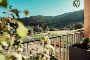 A balcony with a view of a green landscape, including trees and hills.