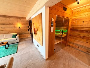 Ein Holzinnenraum mit einer Couch, einem Gemälde, einer Sauna und einer Bedienkonsole.