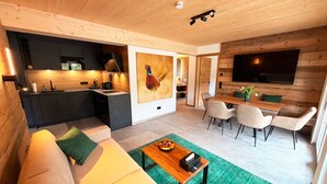 Ein modernes Wohnzimmer mit Sofa, Esstisch und Küchenbereich.