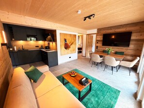 Ein modernes Wohnzimmer mit Sofa, Esstisch und Küchenbereich.