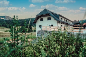 A two-story building with a sloped roof, multiple windows, and a stone foundation.