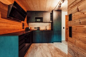 A modern kitchen with wooden accents, a built-in microwave, and a coffee maker.