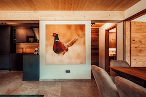 A modern interior with a large wall-mounted bird painting, a wooden ceiling, and a cozy seating area.