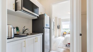 Eine moderne Küche mit weißen Schränken, einem Edelstahlkühlschrank und einer Mikrowelle.