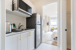 Una cocina moderna con armarios blancos, un refrigerador de acero inoxidable y un microondas.