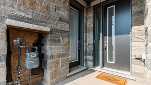 Ein Gebäudehauseingang mit Warmwasserbereiter, einer Tür und einer Fußmatte.