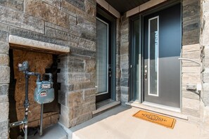 Entrada de un edificio de piedra con calentador de agua, una puerta y felpudo.
