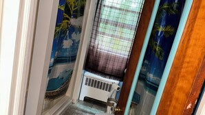 Een badkamer met toilet, een douchegedeelte en een raam met gordijnen.