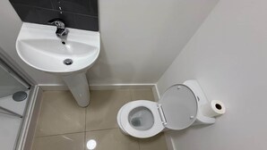 A small bathroom with a toilet, sink, and a mirror. - Radstock Road - Room 2 (Southampton)