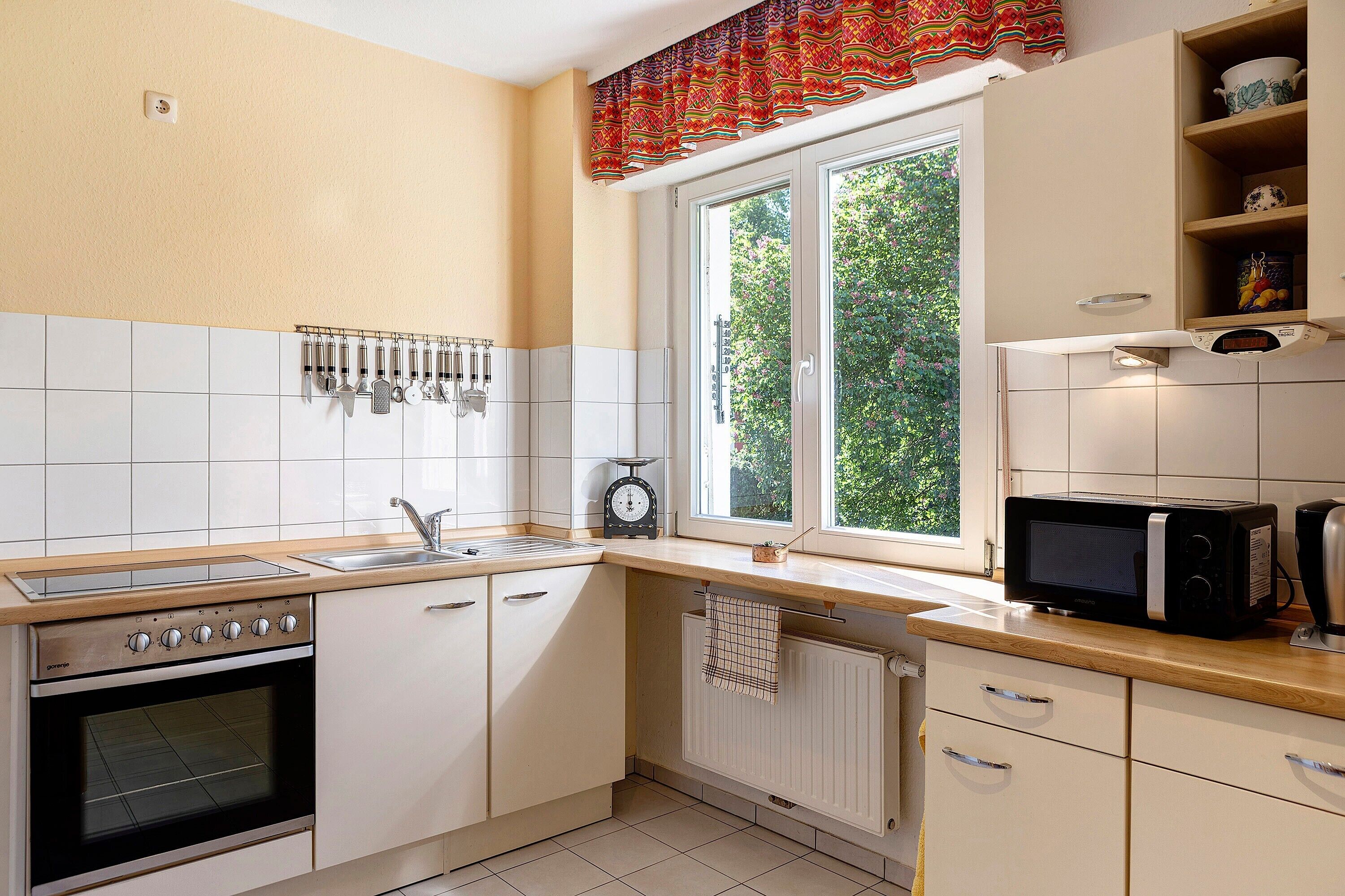 Une cuisine équipée d’une cuisinière, d’un four, d’un four à micro-ondes et d’une fenêtre donnant sur un paysage verdoyant.