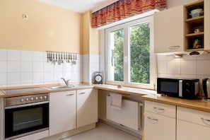 A kitchen with a stove, oven, microwave, and a window with a view of greenery.