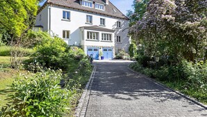 Een huis met twee verdiepingen en een geplaveid opritje dat leidt naar een blauwe deur.
