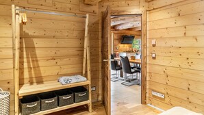 A wooden interior with a wooden bench, storage baskets, and a dining area with chairs and a table. - Chalet "Weiss" with Mountain Views, Private Garden, and Wi-Fi (Wörgl)