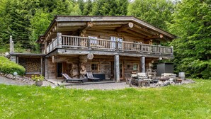 A log cabin with a balcony, outdoor seating, and a stone foundation. - Chalet "Weiss" with Mountain Views, Private Garden, and Wi-Fi (Wörgl)