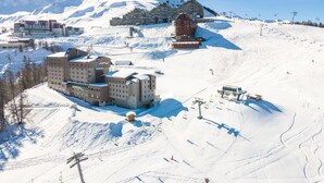 A snow-covered ski resort with multiple buildings, including a large hotel with multiple floors and a ski lift area. - Modern Twin Room With Ski Facilities (La Plagne-Tarentaise)