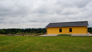 A yellow building with a tiled roof in a grassy field. - Ferienwohnungen in Filz in der Eifel (Filz)