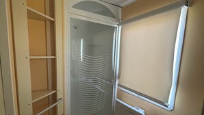 A compact bathroom with a shower, a sink, and a mirror.