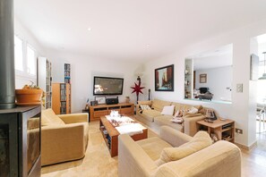 A modern living room with a sofa set, a flat-screen TV, a bookshelf, and a fireplace. - La Villa des Criques Private Pool & Walking Beach (Saint-Raphaël)