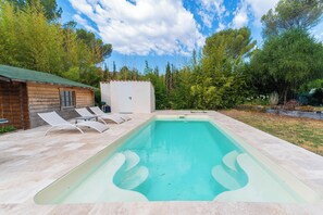 A rectangular swimming pool with two lounge chairs on one side, a small wooden cabin, and a white shed in a garden setting. - La Villa des Criques Private Pool & Walking Beach (Saint-Raphaël)