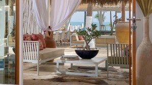 A beachside lounge with a white sofa, a table with a bowl, and a view of the ocean. - Private oceanfront retreat in Jericoacoara with luxury suites (Jijoca de Jericoacoara)