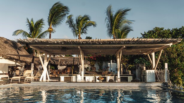 A pool area with lounge chairs, a covered seating area, and palm trees. - Private oceanfront retreat in Jericoacoara with luxury suites (Jijoca de Jericoacoara)