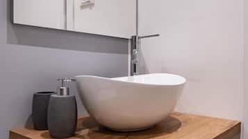 A bathroom with a white sink, a wooden countertop, a mirror, and a towel rack.