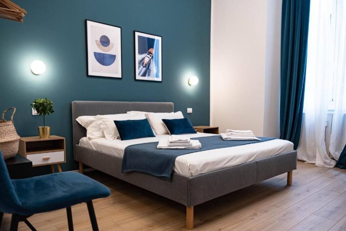 Ein modernes Schlafzimmer mit einem Bett, Nachttischen, einem Sessel und Wandbildern.