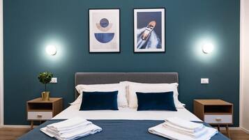 Une chambre d’hôtel comprenant un lit, deux tables de chevet, une plante en pot et deux appliques murales.