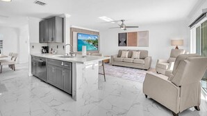 A modern kitchen with a central island, grey cabinets, and a large flat-screen TV. - 6BR Villa Tropical Haven Private Pool & BBQ (Homestead)