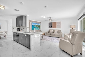A modern kitchen with a central island, grey cabinets, and a large flat-screen TV.