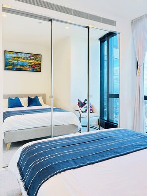 A modern bedroom with a large bed, a seating area with a chair, a painting on the wall, and a large window with a view. - Panoramic City & Bay Views and Free Parking (Southbank)