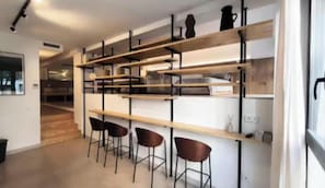 Een modern interieur met een keukenhoek, houten planken en barstoelen.