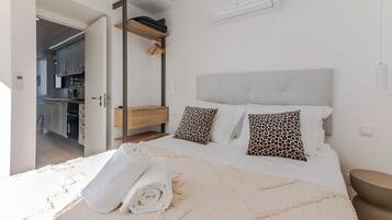 A bedroom with a bed, pillows, a towel, a wardrobe, and an air conditioning unit.