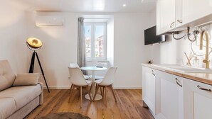 A modern kitchen with white cabinets, a built-in TV, and a window with curtains. - White Angels by Portas do Sol Apartments (Lisbon)