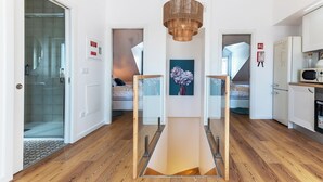 A modern interior with a wooden floor, a central light fixture, and a painting on the wall. - White Angels by Portas do Sol Apartments (Lisbon)