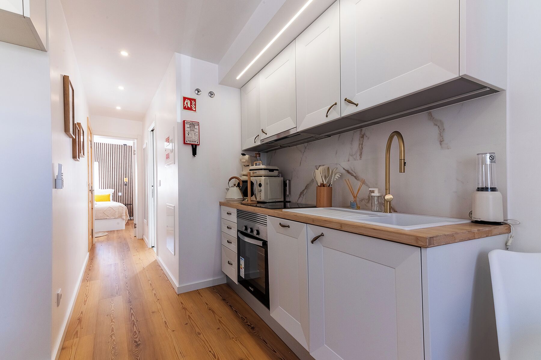 A compact kitchen with white cabinets, a wooden countertop, and modern appliances.