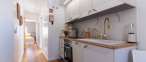 A compact kitchen with white cabinets, a wooden countertop, and modern appliances.