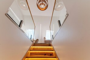 Eine moderne Treppe mit Holzdielen und Glasgeländern, die zu einem Raum mit Aussicht führt.