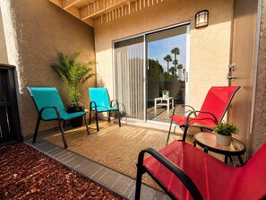 A patio with two chairs, a table, and a potted plant.