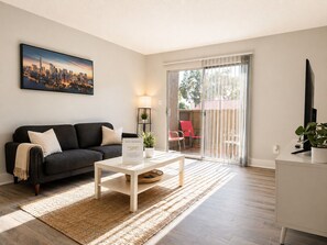 A modern living room with a sofa, coffee table, and a cityscape painting.