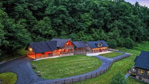 Ein großes Chalet mit mehreren Gästezimmern, einem zentralen Gebäude mit Veranda und einem gepflegten Rasen.