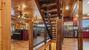 Ein Holzinnenraum mit einer Treppe, einer Küche mit Edelstahlgeräten und einer Sitzecke mit Sofa und Couchtisch.